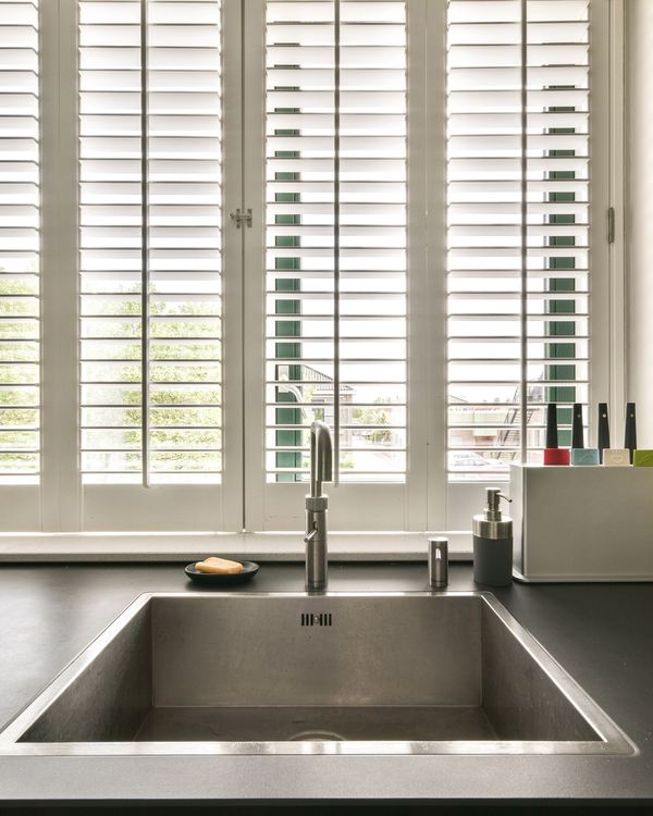 Shutters fitted at a kitchen sink window with daylight coming through the louvres
