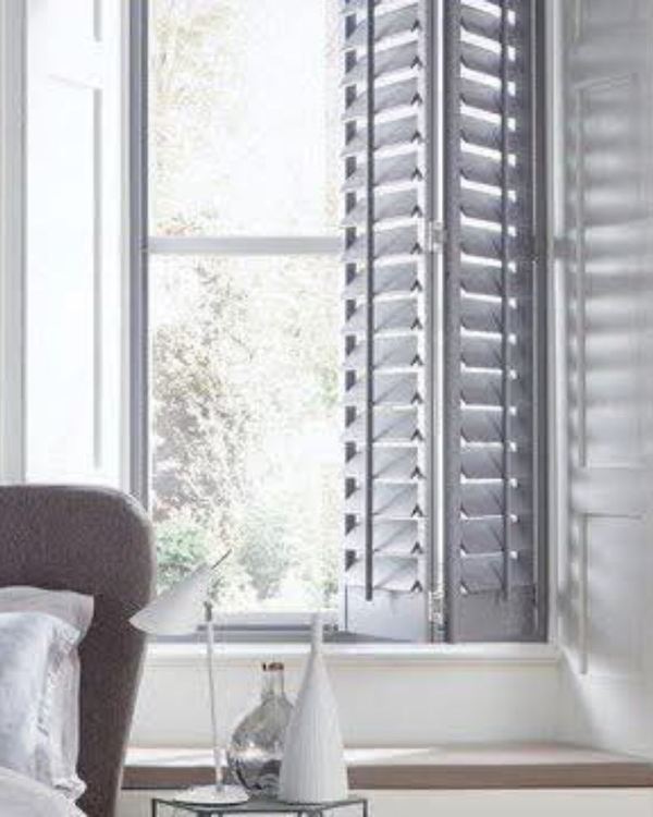 Grey tier-on-tier shutters at a tall bedroom window