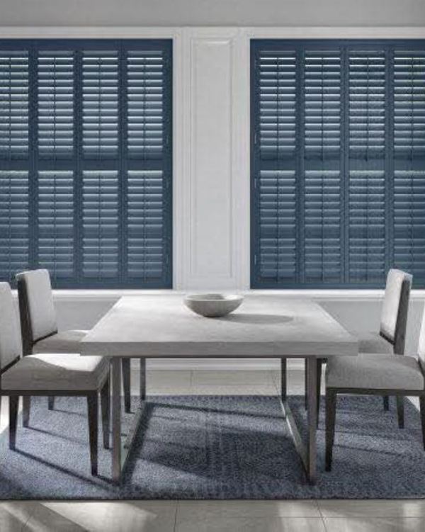 Deep navy full-height shutters in a pale dining room