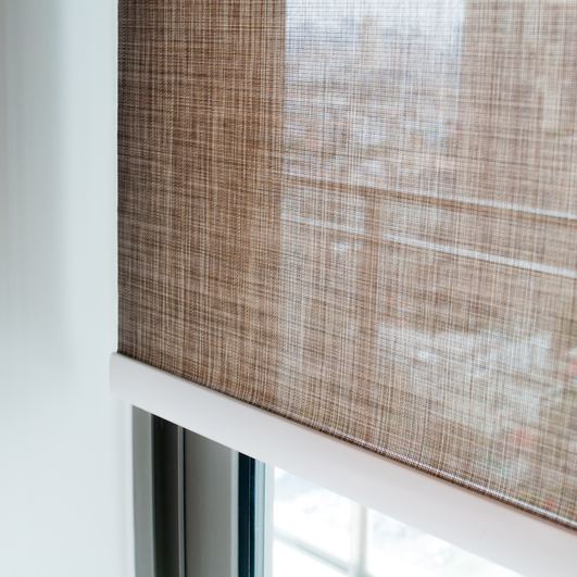 Roller blind in a warm neutral fabric, part-lowered over a window